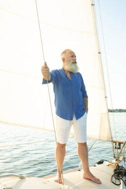 Yelkencilik, yaş, turizm, seyahat ve insanlar konsepti. Sakallı yaşlı adam gölde yüzen yelkenli ya da yatta.