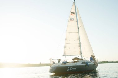 Denize açılıp gölde yelkenli bir teknenin direksiyonunda oturan mutlu bir çift..