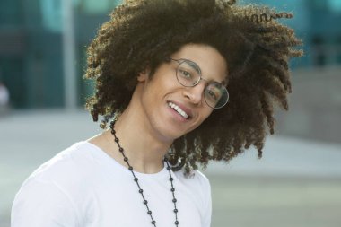 Dışarıda gülümseyen kıvırcık saçlı yakışıklı siyahi adamın yakın portresi..