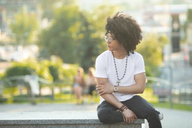 Dışarıda gülümseyen kıvırcık saçlı yakışıklı siyahi adamın yakın portresi..