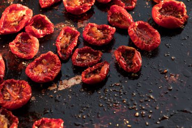 Küçük parçalar halinde güneşte kurutulmuş domatesler koyu arkaplanda metal bir kapta yatıyor. Sağlıklı yemek..