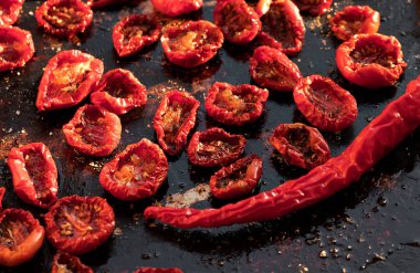 Küçük parçalar halinde güneşte kurutulmuş domatesler koyu arkaplanda metal bir kapta yatıyor. Sağlıklı yemek..