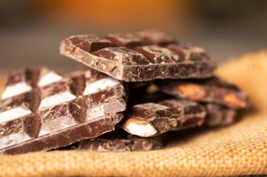 Ahşap arka planda kırılmış çikolata parçaları. Seçici odak.