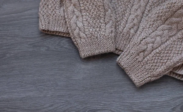 Knitted warm sweaters on wooden table.