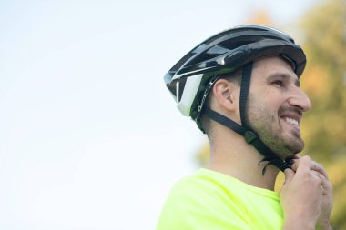 Yakışıklı genç adam parkta bisiklet kaskı takıyor..