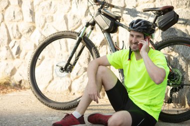 Kiralık bisikletle sokakta oturan sakallı bir adam akıllı telefondan iletişim kuruyor..