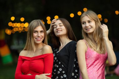 Moda kıyafetleri içinde gülümseyen üç güzel kızın portresi..