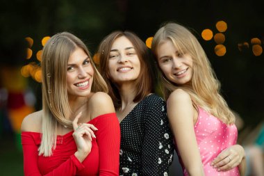 Moda kıyafetleri içinde gülümseyen üç güzel kızın portresi..