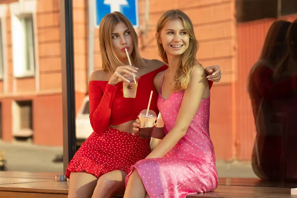İki güzel genç kadın kokteyl içiyor ve sıcak yaz gününde eğleniyorlar..