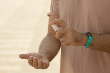 Açık havada dezenfektan kullanan olgun bir adamın yakın görüntüsü