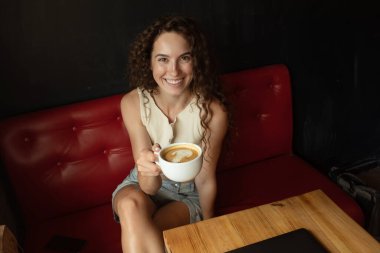 Kafede kahve içen güzel kızıl saçlı kadın.