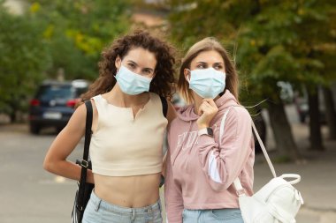 Coronavirus, Covid-19 tarafından korunmak için yüz maskesi takan iki genç arkadaş sokakta buluştu ve güvenlik mesafesinde kaldı..