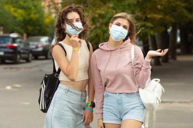 Coronavirus, Covid-19 tarafından korunmak için yüz maskesi takan iki genç arkadaş sokakta buluştu ve güvenlik mesafesinde kaldı..