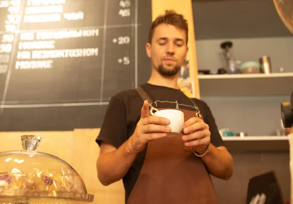 Knappe Barista Schort Met Een Kop Koffie Glimlachend Aan Bar — Stockfoto