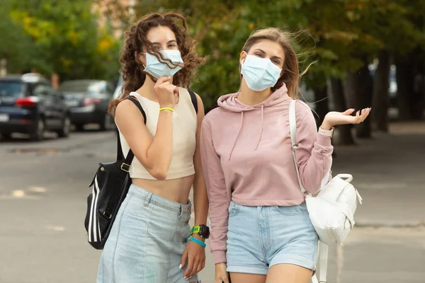 Two young best friends meeting on street wearing a face mask to protection by Coronavirus, Covid-19 and stay security distant.