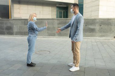 Korumacı yüz maskeleri takan erkek ve kadın birbirlerinden 2 metre uzakta duruyorlar. Sosyal mesafeyi koronavirüsün yayılmasını önlüyorlar. Covid-19. Yeni kurallar.