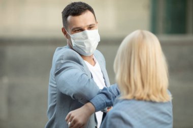 Dirsek çarpması. Coronavirus 'un (COVID-19) yayılmasını önlemek için dirsek seği selamı. Kadın ve erkek çıplak ellerle sokakta buluşurlar. Sarılmak ya da tokalaşmak yerine, dirseklerini vuruyorlar.