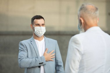 Yüz maskesi takan iki arkadaş, enfeksiyon riski ve hastalık önleme riski olan COVID-19 için açık havada duvara karşı duruyor..