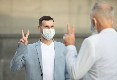 Yüz maskesi takan iki arkadaş, enfeksiyon riski ve hastalık önleme riski olan COVID-19 için açık havada duvara karşı duruyor..