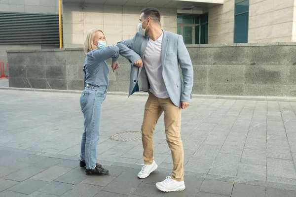 Elbow bumping. Elbow greeting to avoid the spread of coronavirus (COVID-19). Man and woman meet in the street with bare hands. Instead of greeting with a hug or handshake, they bump elbows instead