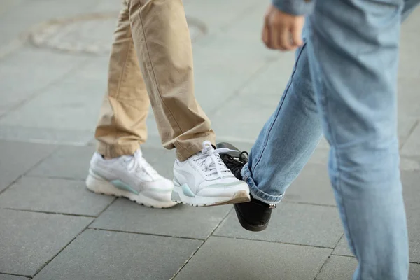 Young people greeting to avoid the spread of coronavirus. Two friends meet, instead of greeting with a hug or handshake, they touch their feet together. Social distance concept. Covid-19.