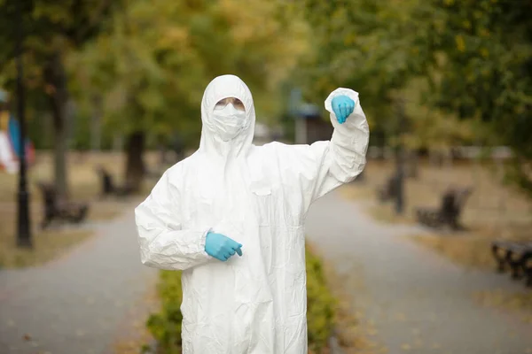 Doctor man in medical suit sterile face mask gloves on street . Epidemic pandemic coronavirus 2019-ncov sars covid-19 flu virus. Pointing finger aside up.