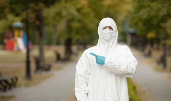 Doctor man in medical suit sterile face mask gloves on street . Epidemic pandemic coronavirus 2019-ncov sars covid-19 flu virus. Pointing finger aside up.