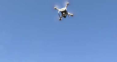 Ormandaki ağaçların arasında uçan beyaz drone.