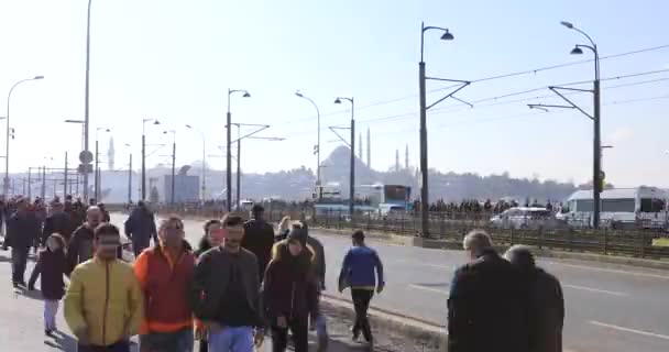 Mucha gente caminando en el puente de Galata Nueva mezquita está en el fondo — Vídeos de Stock