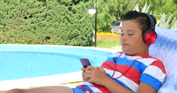 Portrait Cute Teenage Boy Headphone Sitting Sunbed Swimming Pool Using — Stock Video