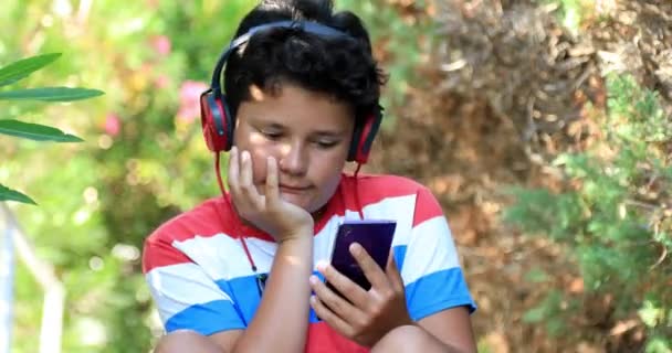 ヘッドフォンが自然で音楽を聴きながら幸せな若者の肖像 — ストック動画