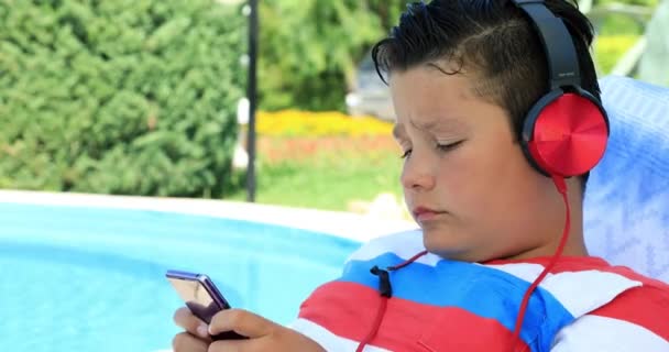 Portrait Cute Teenage Boy Headphone Sitting Sunbed Swimming Pool Using — Stock Video