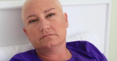 Yatakta, döşeme kadın kanser hastası kameraya bakarak sıkılmış