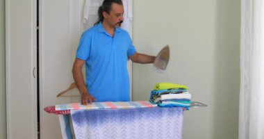 Orta yaşlı adam giyim ile elektrik demir Ütü