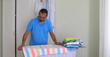 Orta yaşlı adam giyim ile elektrik demir Ütü