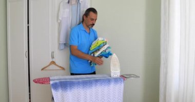 Orta yaşlı adam giyim ile elektrik demir Ütü