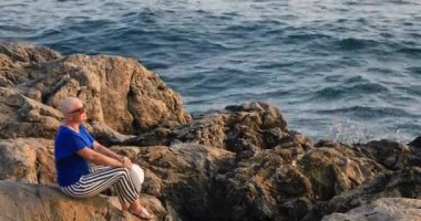 Oturma ve denize yakın rahatlatıcı bir pozitif kadın kanser hastası portresi
