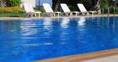 Yüzme havuzunda bir kameraya gülümseyen ve jest Yaşasın gösterilen genç çocuk