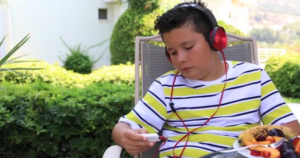 Kulaklıklı Müzik Dinleyen Yeşil Bahçede Farklı Meyveler Yiyen Mutlu Bir — Stok video