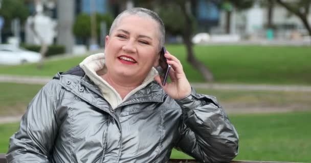 都市公園で携帯電話で話している短い白髪の中年の女性 — ストック動画
