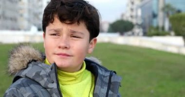 Kış giysileri ile mutlu küçük çocuk portresi gülümseyerek ve kış zamanda parkta kamera poz