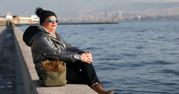 中年妇女与冬季服装坐在岸边线和放松在户外 — 图库视频影像