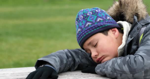 穿着冬衣坐在城市公园里的悲伤孩子 — 图库视频影像