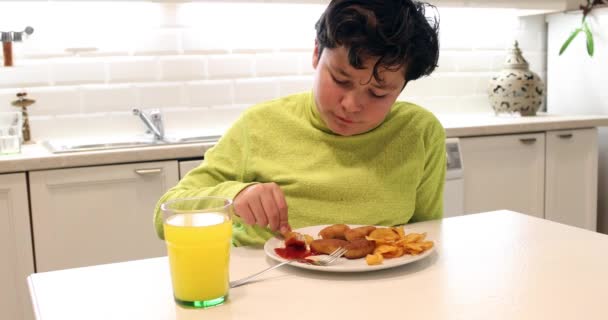 キッチンでチキンナ ゲットとポテトチップスを食べて若い男の子の肖像画 — ストック動画