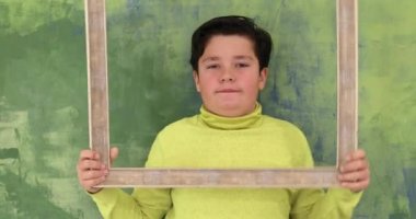 Portre sevimli bir genç çocuğun emty çerçeve seyir ve bir kamera için aptal surat
