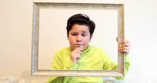 一个英俊的小男孩的肖像 Emty 框架看 并使愚蠢的脸对相机 — 图库视频影像
