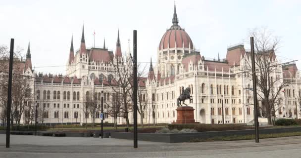 ブダペスト ハンガリー 月17 2019 黄色のトラムが有名なハンガリー国会議事堂のゴシック様式の建築物の前を通過冬時間の外観 — ストック動画