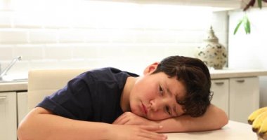 Yalnız mutfakta oturan bir mutsuz preteen çocuk portre.