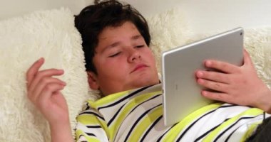 Evde dijital tablet ile kanepede yatan yorgun genç