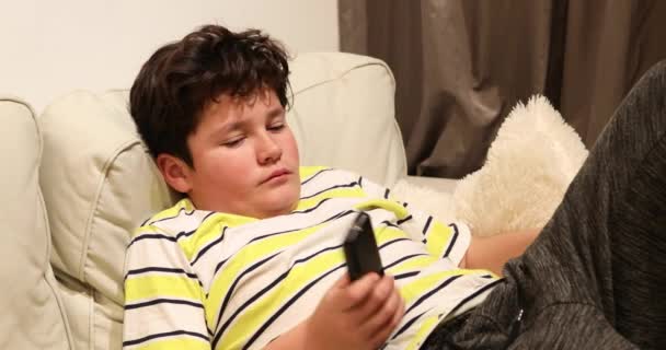 Κουρασμένη έφηβος που βρίσκεται στον καναπέ και βλέποντας τηλεόραση στο σπίτι — Αρχείο Βίντεο